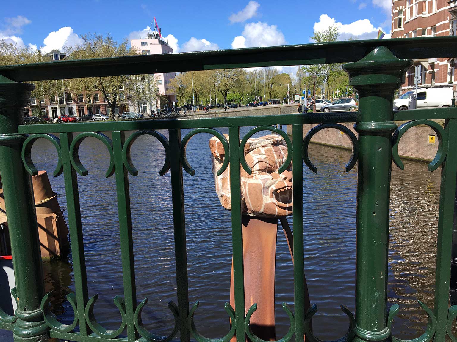 Bullebak statue viewed through the railing of bridge 149, Amsterdam