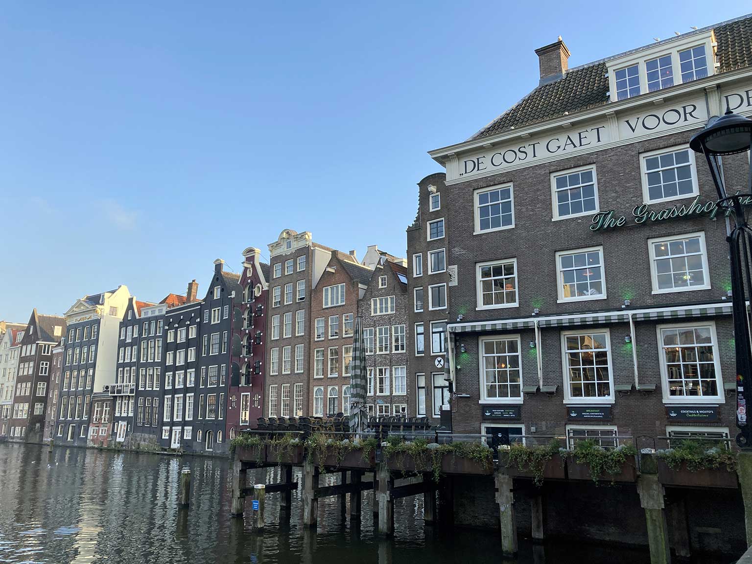 Van Oudebrugsteeg kijkend op de oostkant van het Damrak, Amsterdam, de achterkant van de huizen van de Warmoesstraat in het water