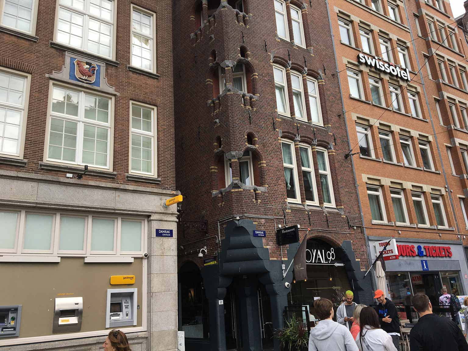 Gevelsteen met hand en haan op Damrak 100, Amsterdam, de Valkensteeg rechts ervan